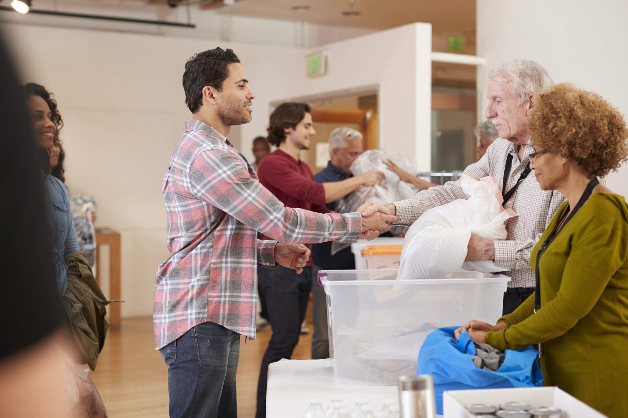 People Donating Clothing To Charity Collection In Community Center